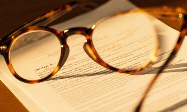 Primer plano de gafas de lectura sobre un contrato legal